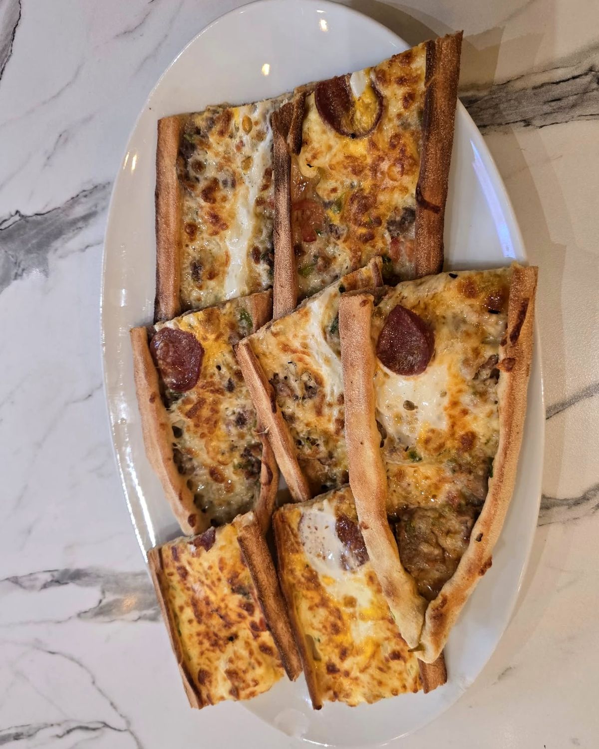 Karışık pide au sucuk, à la viande hachée et au kaşar, coupé en lanières